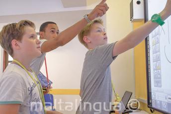 Ein Lehrer hilft 2 jungen Sprachülern am Whiteboard
