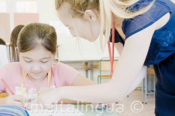 Eine Lehrerin hilft einem Kind im Englischkurs