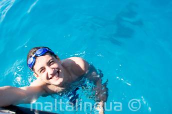 Ein Sprachschüler schwimmt neben dem Boot in Comino