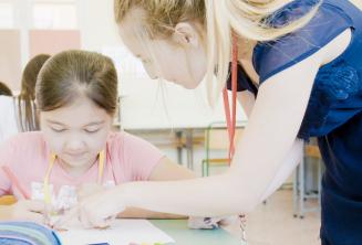 Eine Lehrerin hilft einem Kind im Englischkurs