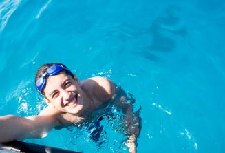 Ein Sprachschüler schwimmt neben dem Boot in Comino